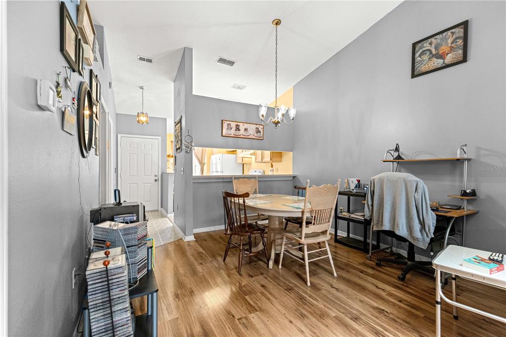 A dining area with wood flooring, a round table, and a desk against the wall — 10483 SW 85TH COURT, OCALA, FL