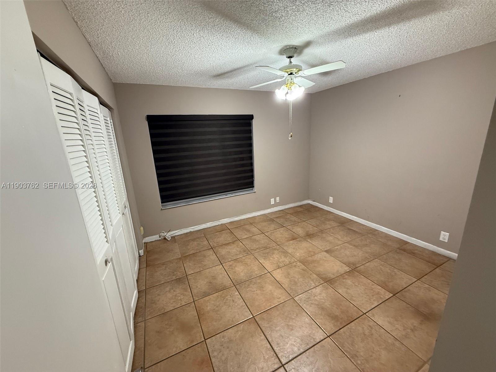 A hallway with tan tile flooring leads to a doorway and a closet — 9422 SW 127th Ave, Miami FL 33186, MIAMI, FL