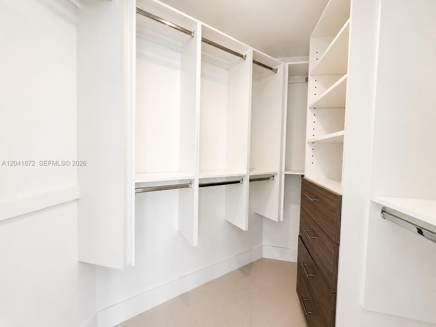 A walk-in closet features white shelving, hanging rods, and a dark wood drawer unit — 1010 SW 2nd Ave # 1504, Miami FL 33130, MIAMI, FL