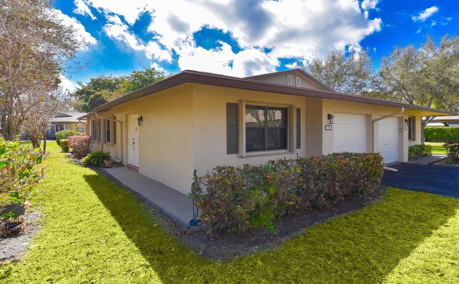 A single-story tan house with a brown roof, a front porch, and two garage doors — 1630 Palmland Drive, Boynton Beach FL 33436, BOYNTON BEACH, FL