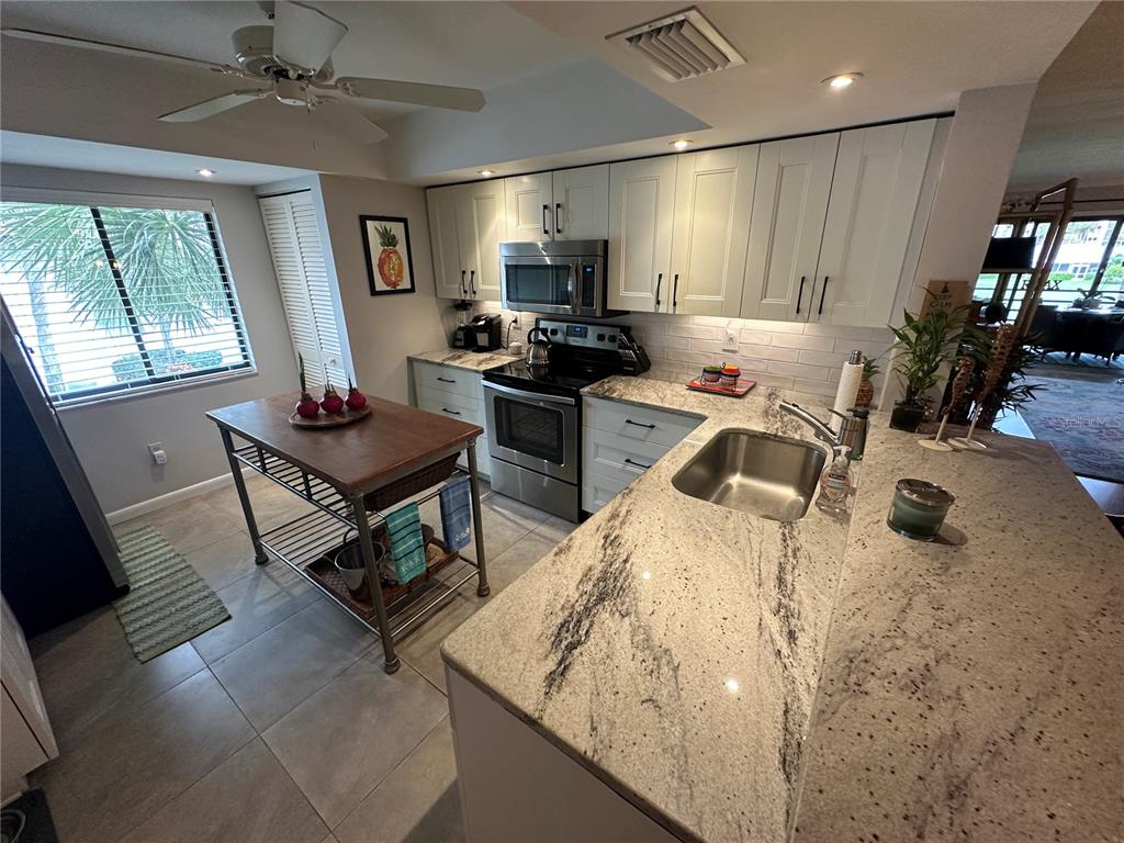 A kitchen features white cabinets, granite countertops, stainless steel appliances, and a wooden island — 3500 EL CONQUISTADOR PARKWAY UNIT 344, BRADENTON, FL