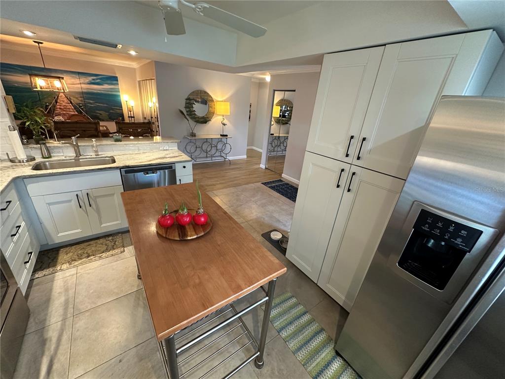 A kitchen features a wooden island, stainless steel appliances, white cabinetry, and tile flooring — 3500 EL CONQUISTADOR PARKWAY UNIT 344, BRADENTON, FL