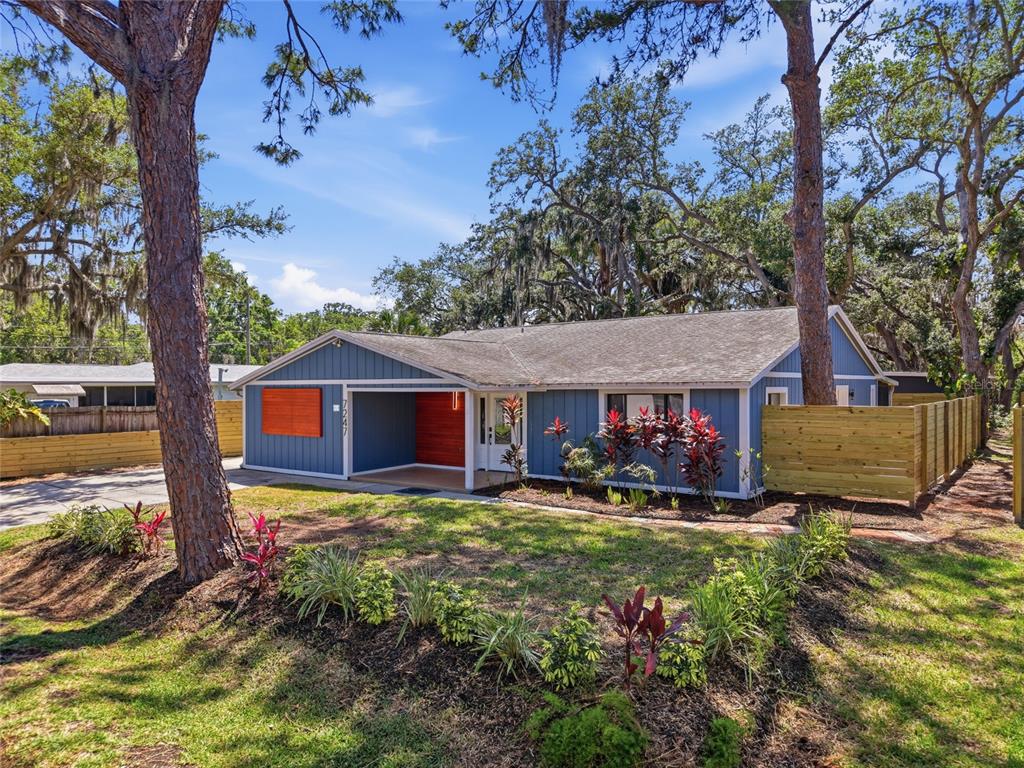 A blue single-story house with a covered entryway and a wooden fence in the yard — 7247 OELSNER STREET, NEW PORT RICHEY, FL