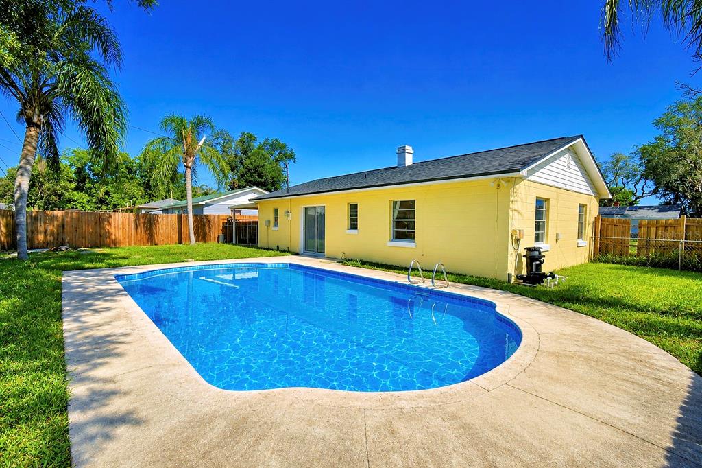 A yellow house with a swimming pool in the backyard under a clear blue sky — 1306 BRYN MAWR AVENUE, LAKE WALES, FL