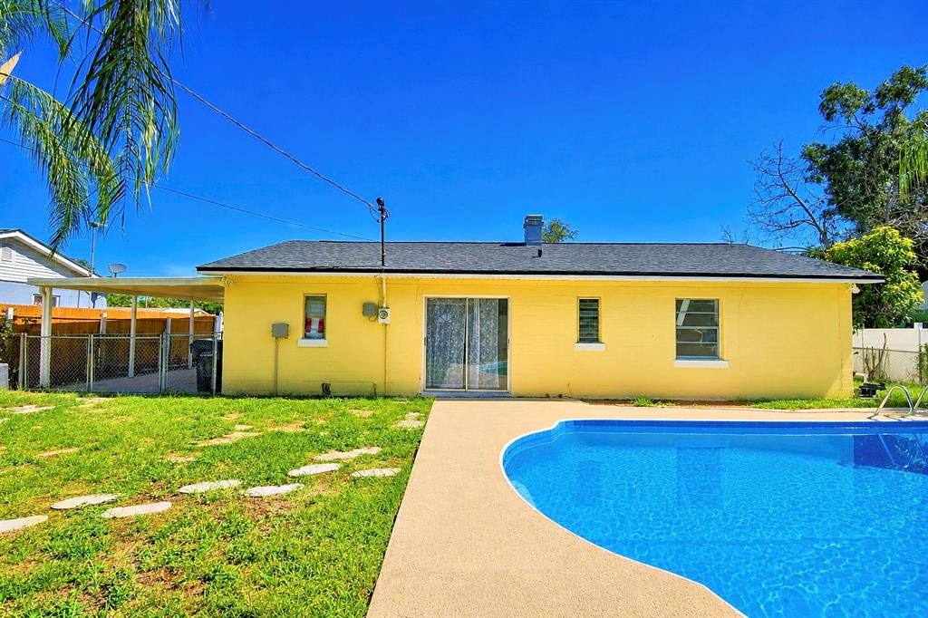 The back exterior of a yellow house features a swimming pool and a covered patio — 1306 BRYN MAWR AVENUE, LAKE WALES, FL