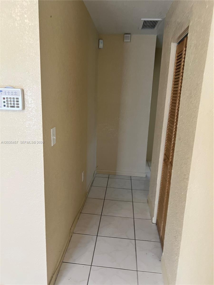 A narrow hallway features beige walls, white tile flooring, and a louvered closet door — 789 NW 55th Ter # B, Miami FL 33127, MIAMI, FL