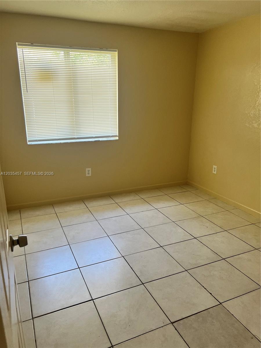 An empty room features beige walls, a single window with blinds, and light-colored tile flooring — 789 NW 55th Ter # B, Miami FL 33127, MIAMI, FL