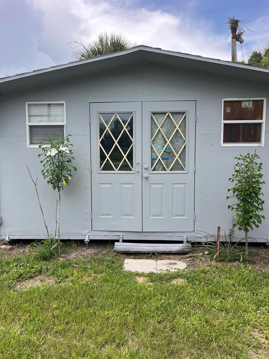 A light gray shed with double doors, two windows, and a small wooden step — 8956 SE 65th Way SE, Okeechobee FL 34974, OKEECHOBEE, FL