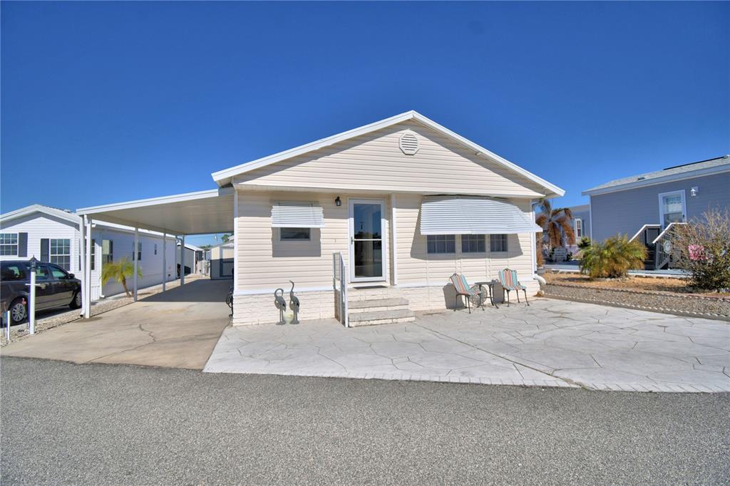 A light-colored mobile home features a carport, a concrete patio, and a front entrance — 251 PATTERSON ROAD UNIT B26, HAINES CITY, FL