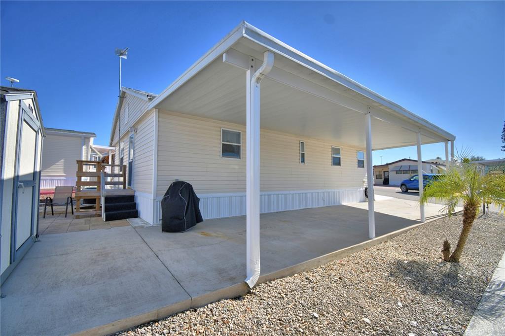 A side view of a mobile home featuring a covered carport and a small patio — 251 PATTERSON ROAD UNIT B26, HAINES CITY, FL