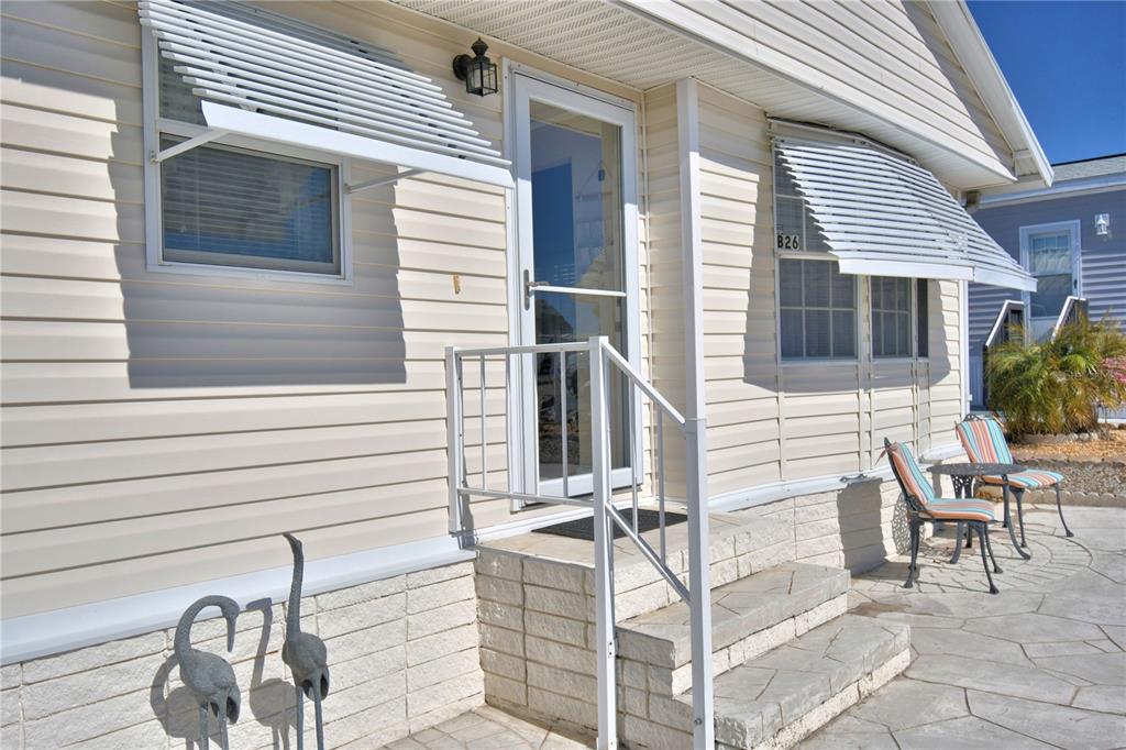 The exterior of a beige mobile home features white awnings, stone steps, and patio furniture — 251 PATTERSON ROAD UNIT B26, HAINES CITY, FL