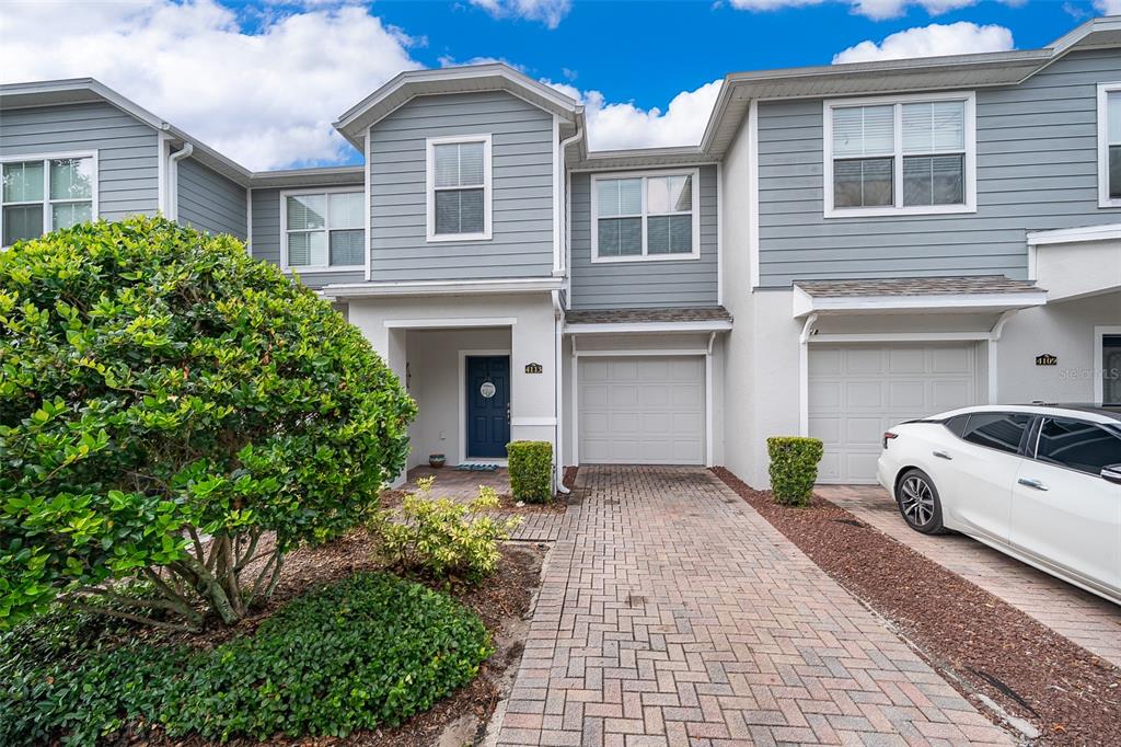 A two-story townhouse exterior features gray siding, white trim, a brick driveway, and a garage — 4113 HEDGE MAPLE PLACE, WINTER SPRINGS, FL