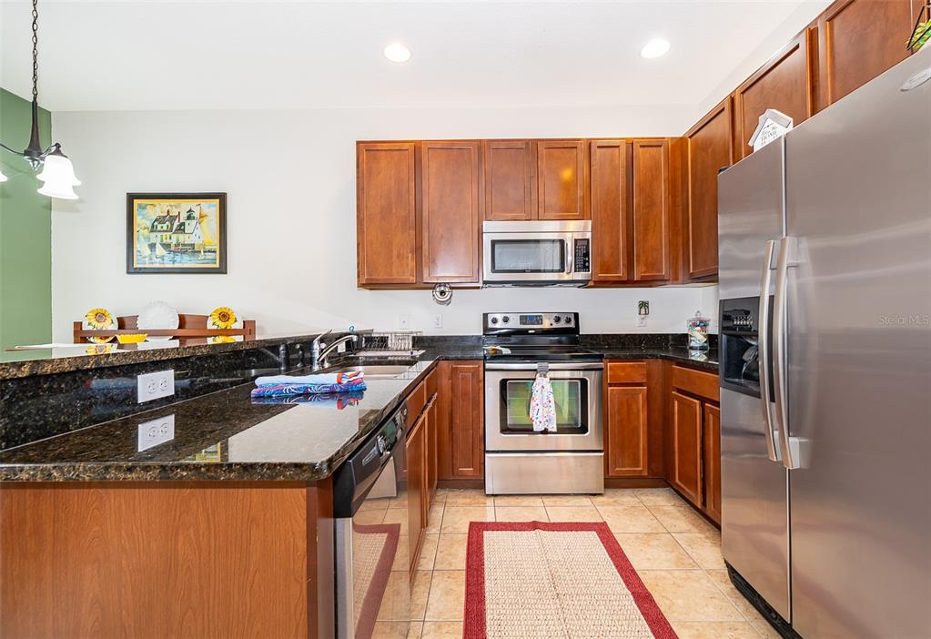 A kitchen with wood cabinets, stainless steel appliances, and dark granite countertops — 4113 HEDGE MAPLE PLACE, WINTER SPRINGS, FL