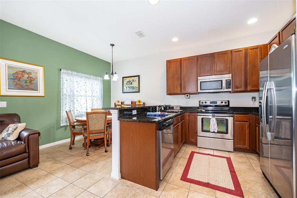 A kitchen with wood cabinets, stainless steel appliances, and a dining area with green walls — 4113 HEDGE MAPLE PLACE, WINTER SPRINGS, FL