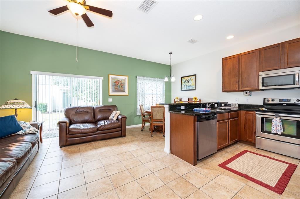 A kitchen with wood cabinets and stainless steel appliances opens to a living and dining area — 4113 HEDGE MAPLE PLACE, WINTER SPRINGS, FL