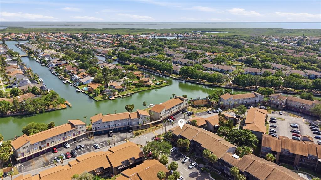 An aerial view shows multi-story residential buildings situated along a canal near a large body — 6336 NEWTOWN CIRCLE UNIT 36C1, TAMPA, FL