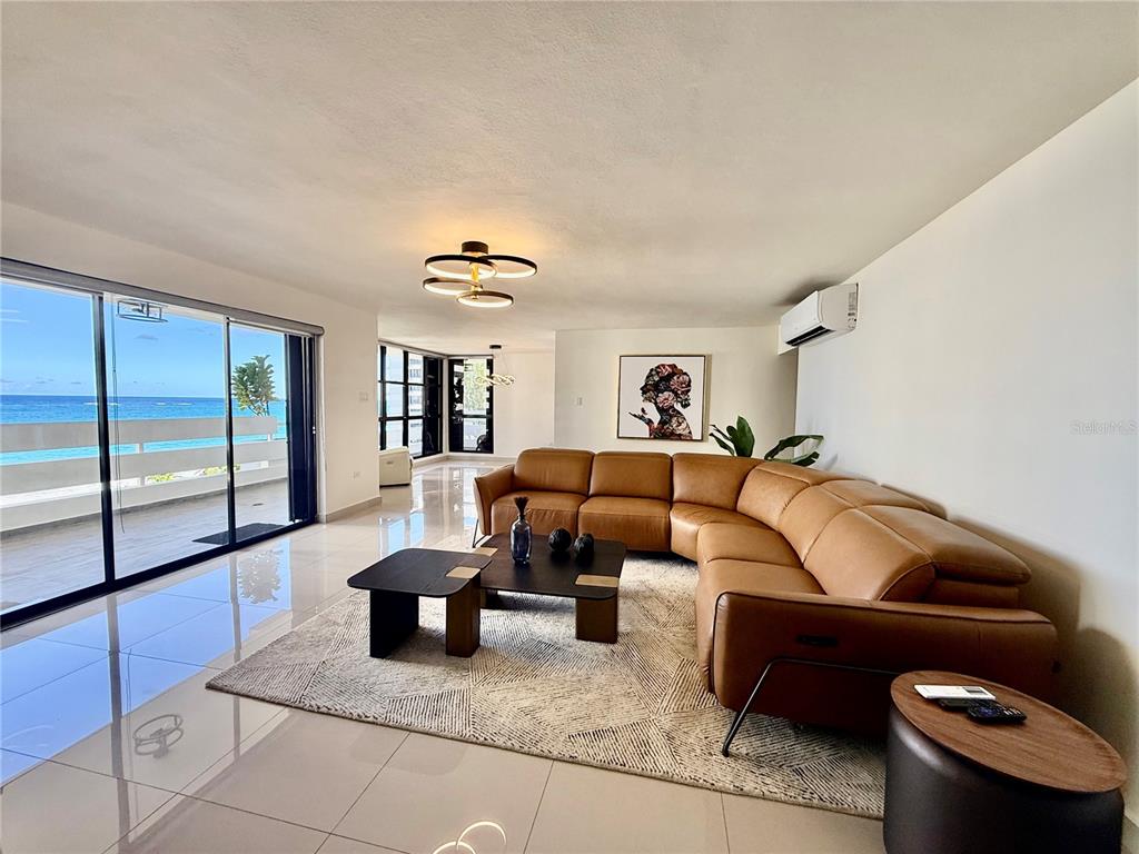 A living room features a tan sectional sofa, a geometric rug, and a balcony view — 1510 ASHFORD AVENUE UNIT 7E, SAN JUAN, PR