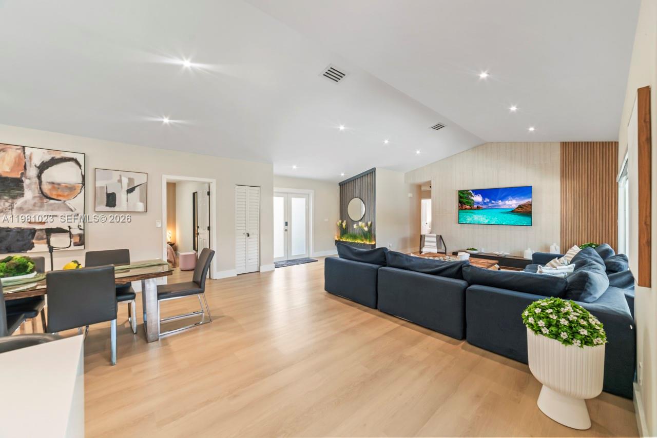A living and dining area features light wood flooring, a blue sectional, and wood-paneled walls — 14481 SW 161st St, Miami FL 33177, MIAMI, FL