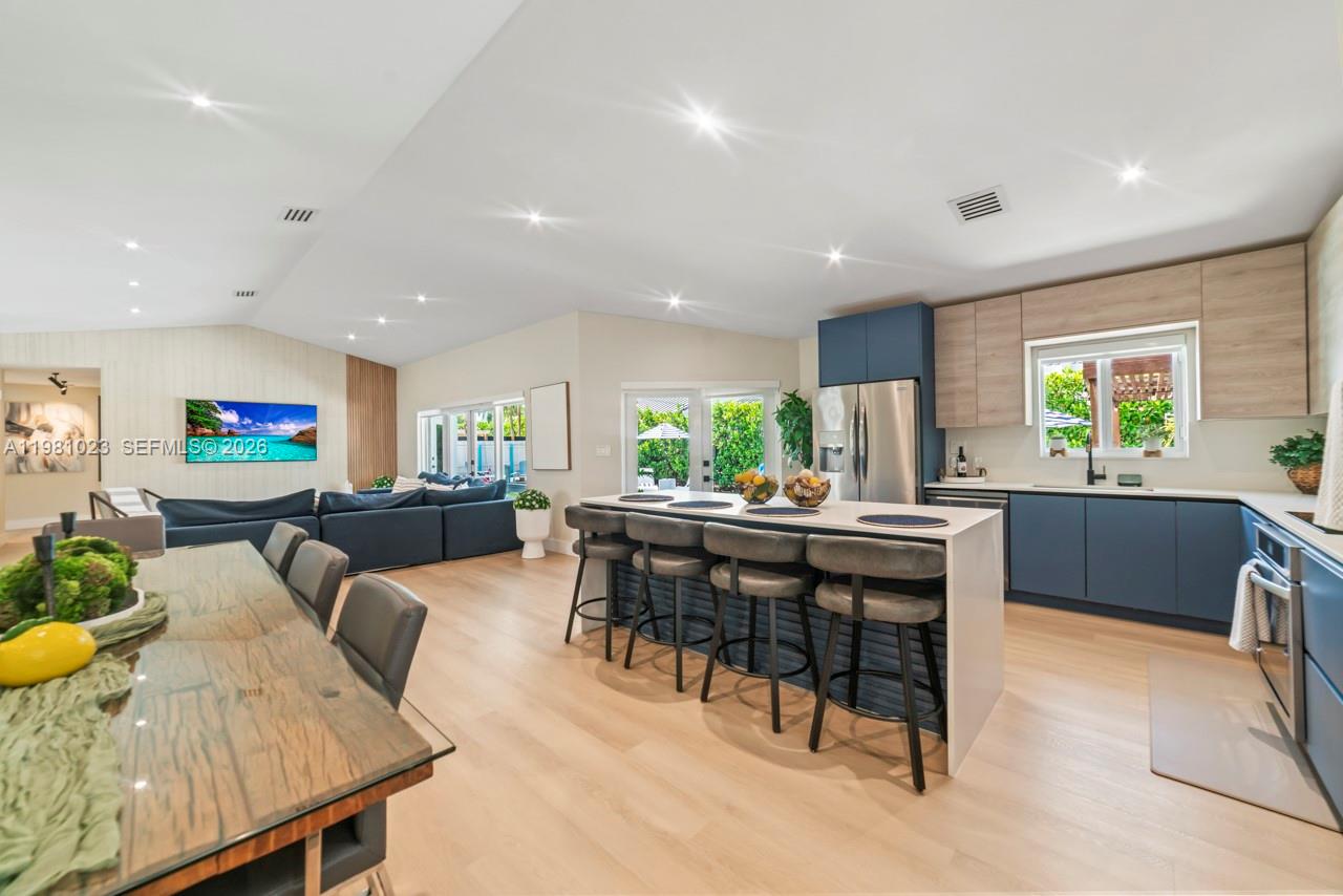 An open-concept kitchen and living area features a central island, blue cabinetry, and wood flooring — 14481 SW 161st St, Miami FL 33177, MIAMI, FL