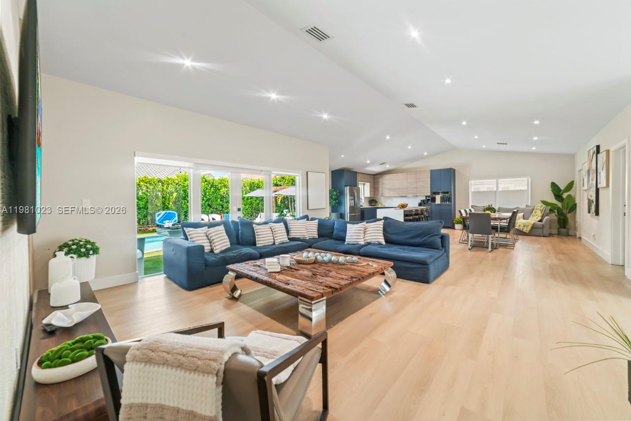 A spacious open-concept living room features a large blue sectional, wood coffee table, and kitchen — 14481 SW 161st St, Miami FL 33177, MIAMI, FL