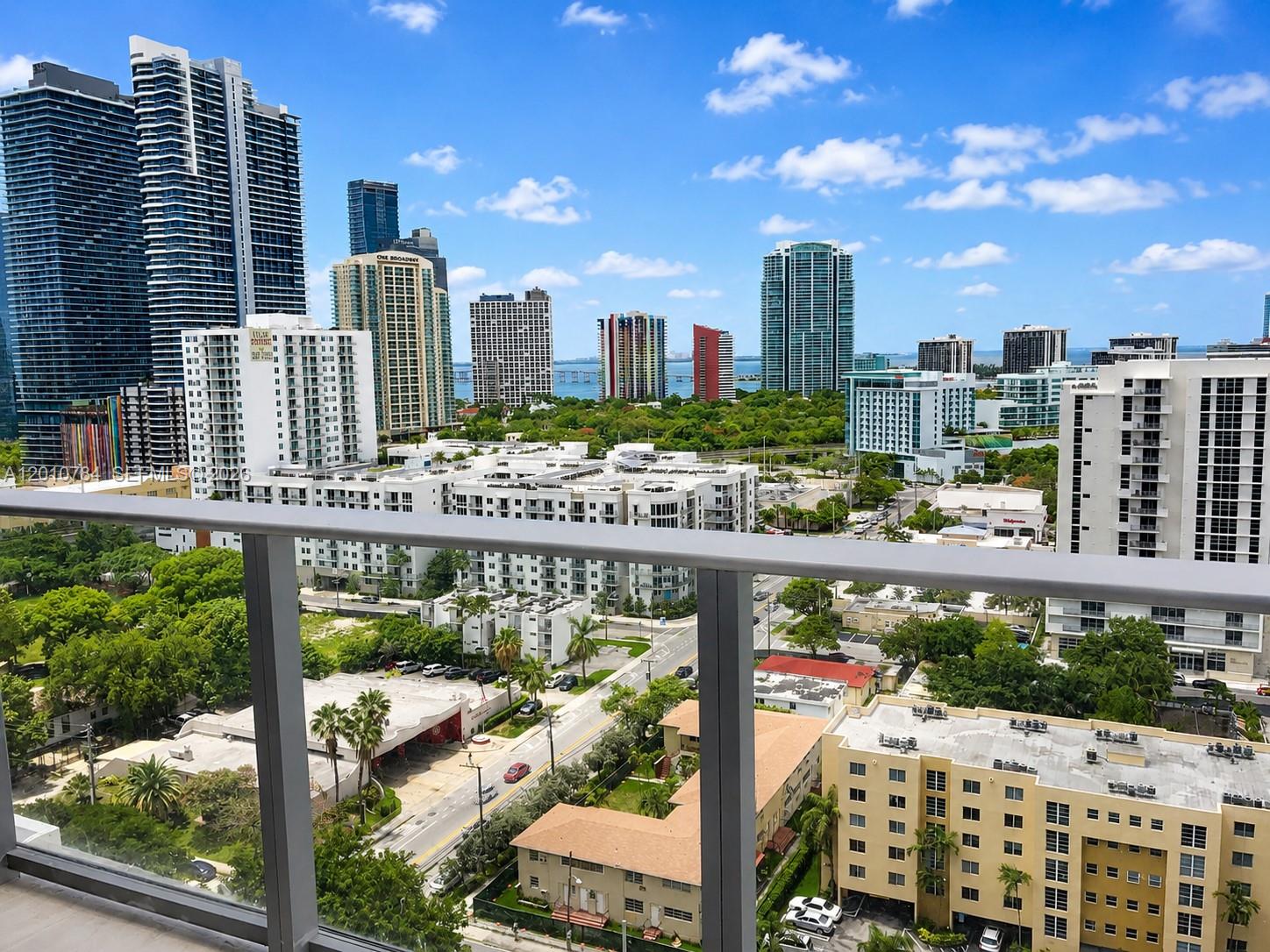 An elevated view from a balcony overlooking a city skyline, lush trees, and urban streets — 1010 SW 2nd Ave # 1809, Miami FL 33130, MIAMI, FL
