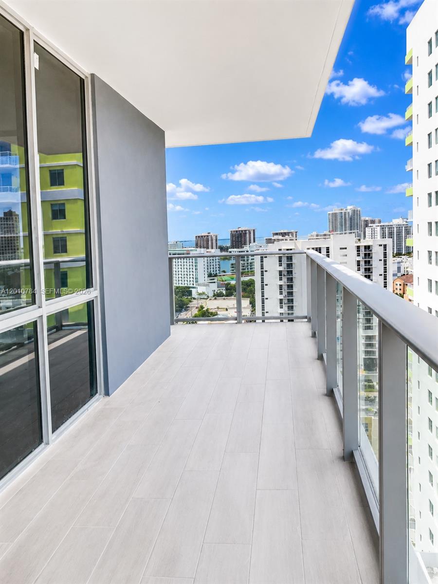 A balcony with light-colored tile flooring overlooks a city skyline and a body of water — 1010 SW 2nd Ave # 1809, Miami FL 33130, MIAMI, FL