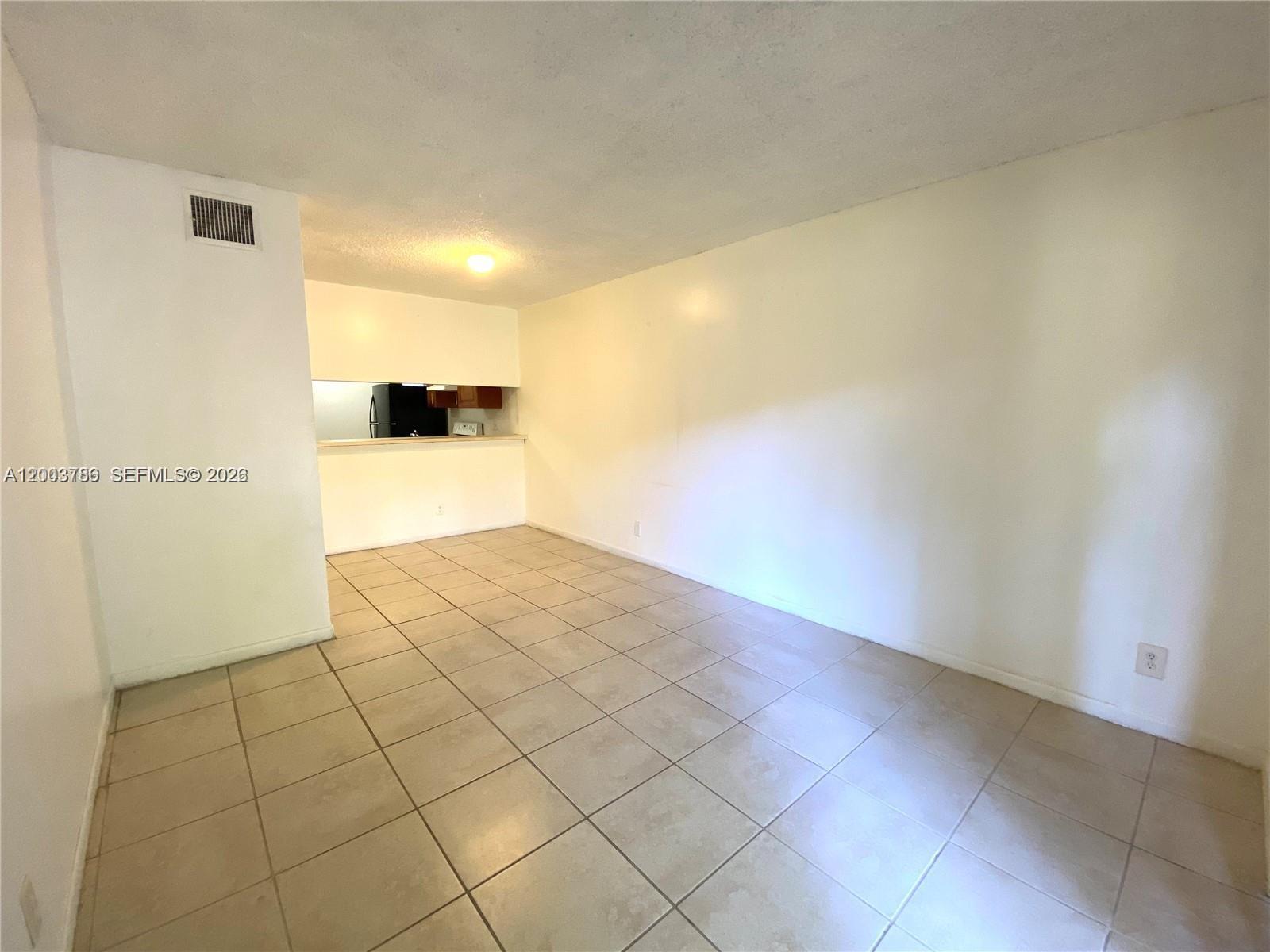 This room features light-colored floor tiles, white walls, and an opening to a kitchen area — 4033 Lakeside Dr # 4033, Tamarac FL 33319, TAMARAC, FL