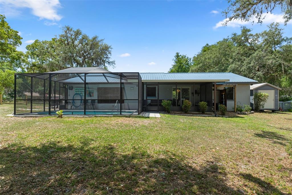 A backyard view of a single-story house featuring a screened-in pool and a storage shed — 2481 S SUMMERWOOD POINT, INVERNESS, FL