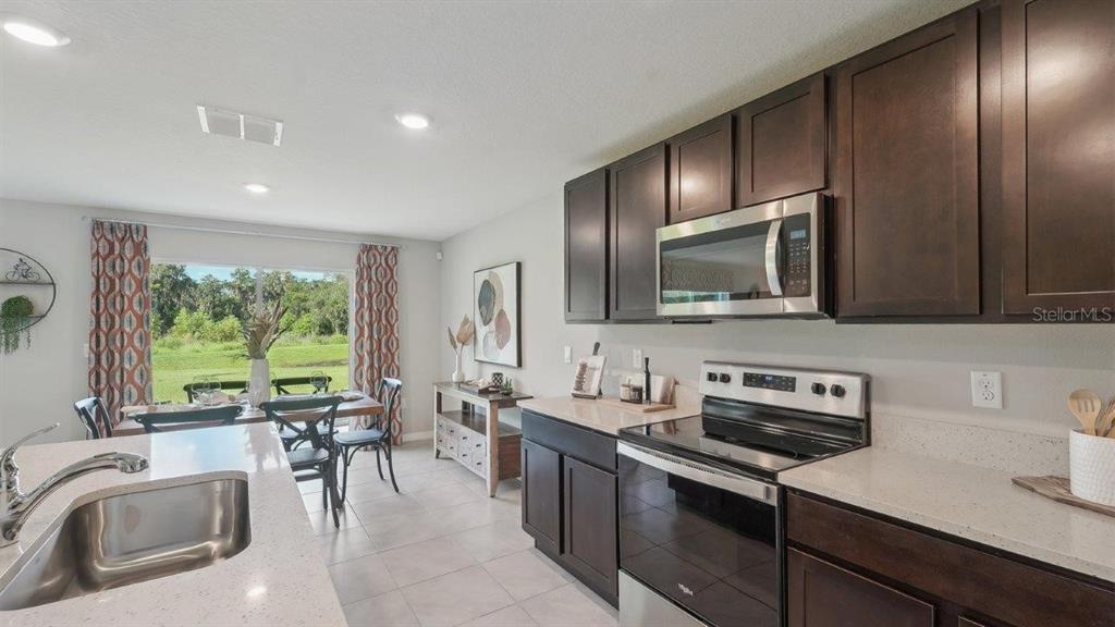 A kitchen with dark wood cabinets, stainless steel appliances, and a view of the outdoors — 35101 VALLEY RIDGE ROAD, DADE CITY, FL