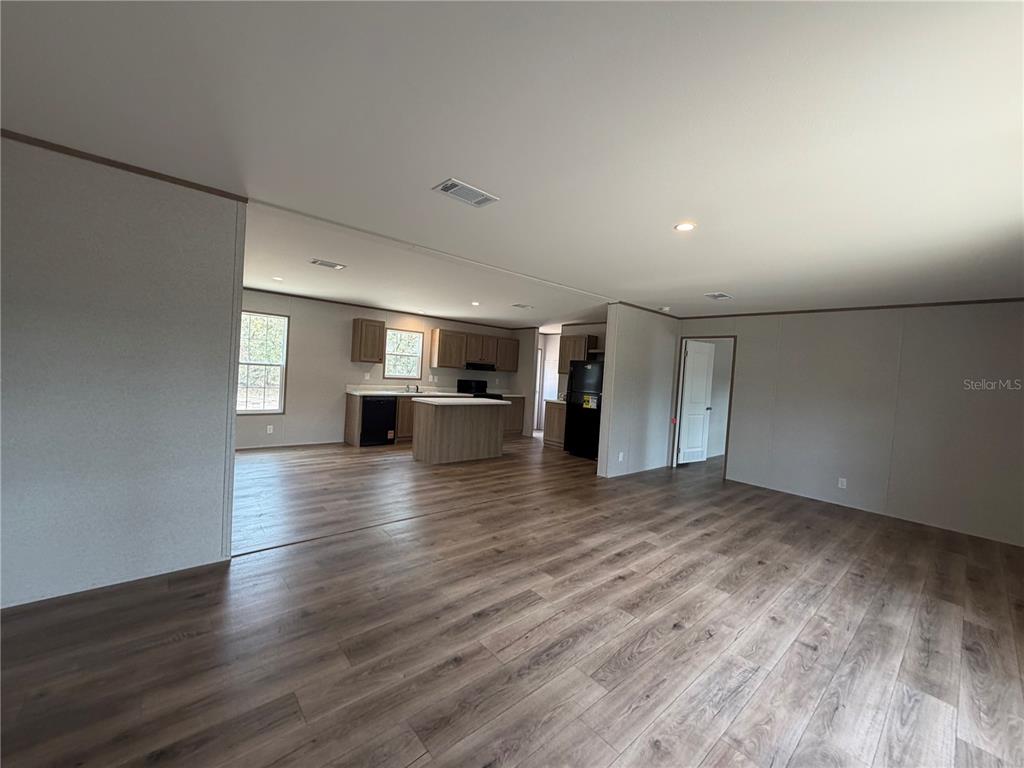 An open-concept living area flows into a kitchen with wood-look flooring and light-toned cabinetry — 2671 SE 133RD TERRACE, MORRISTON, FL