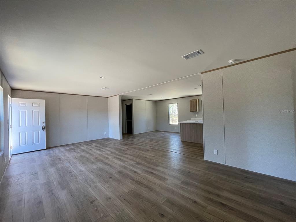 An open-concept living area features light-colored walls, wood-look flooring, and a kitchen island — 2671 SE 133RD TERRACE, MORRISTON, FL