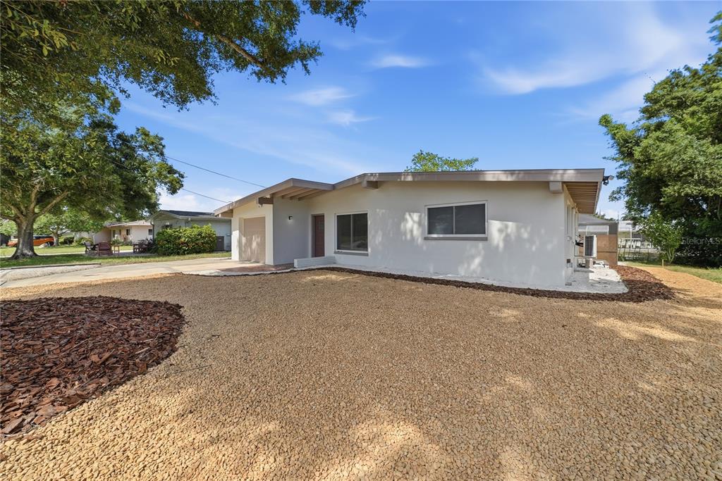 A single-story house with a white exterior, gravel front yard, and an attached garage — 197 OVERBROOK DRIVE E, LARGO, FL