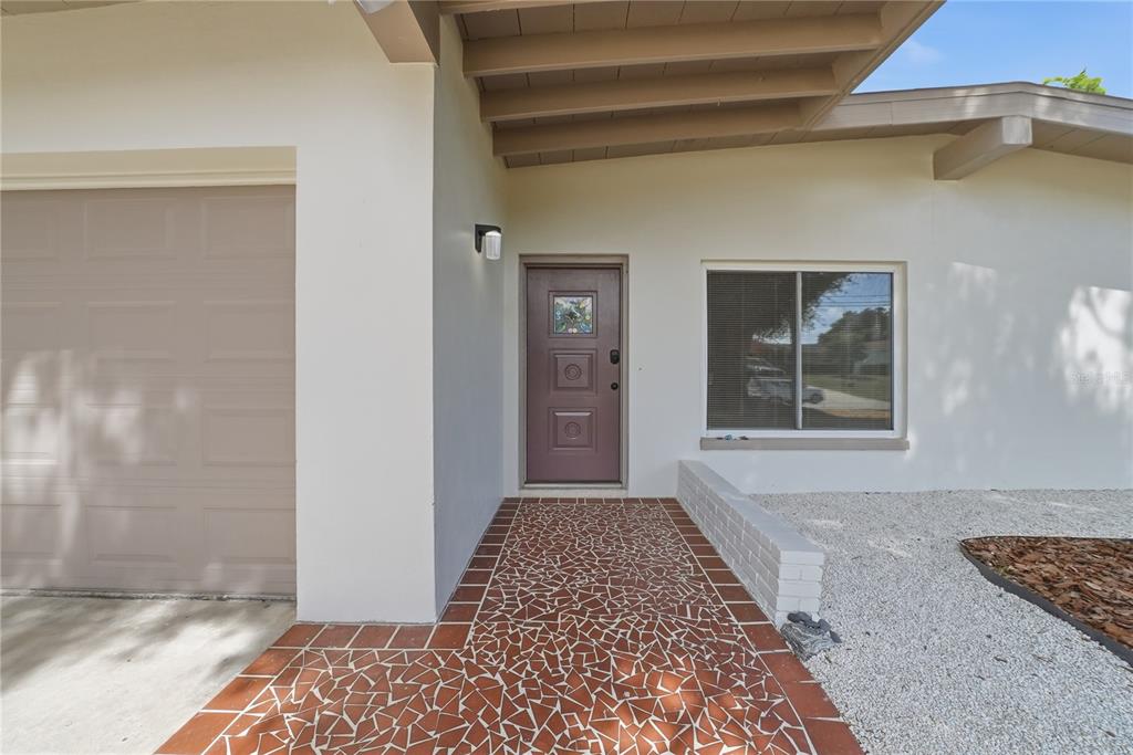 A front entryway features a brown door, tiled walkway, and a garage on the left — 197 OVERBROOK DRIVE E, LARGO, FL