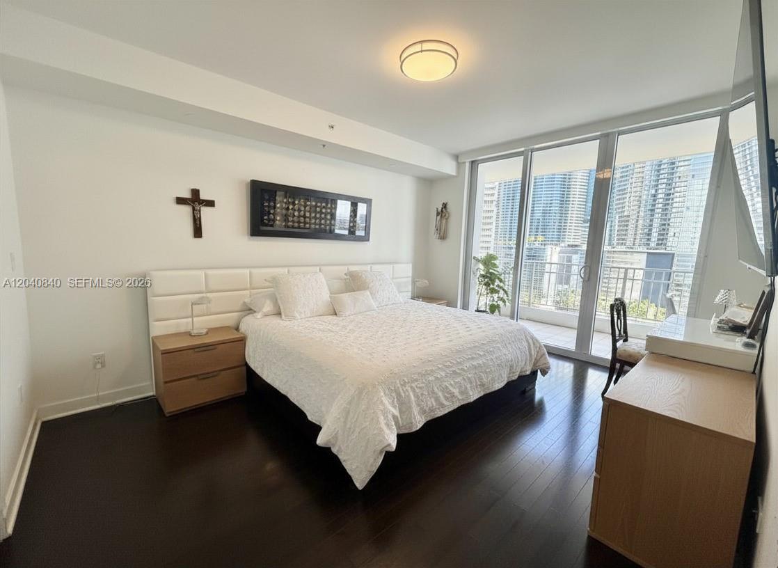 A bedroom features a white upholstered headboard, dark wood floors, and floor-to-ceiling windows — 801 Brickell Key Blvd # 1704, Miami FL 33131, MIAMI, FL