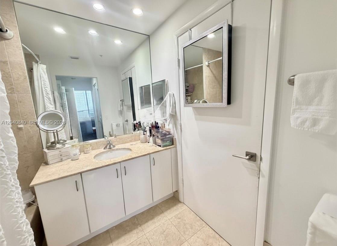 A bathroom features a vanity with a beige countertop, a large mirror, and white cabinets — 801 Brickell Key Blvd # 1704, Miami FL 33131, MIAMI, FL