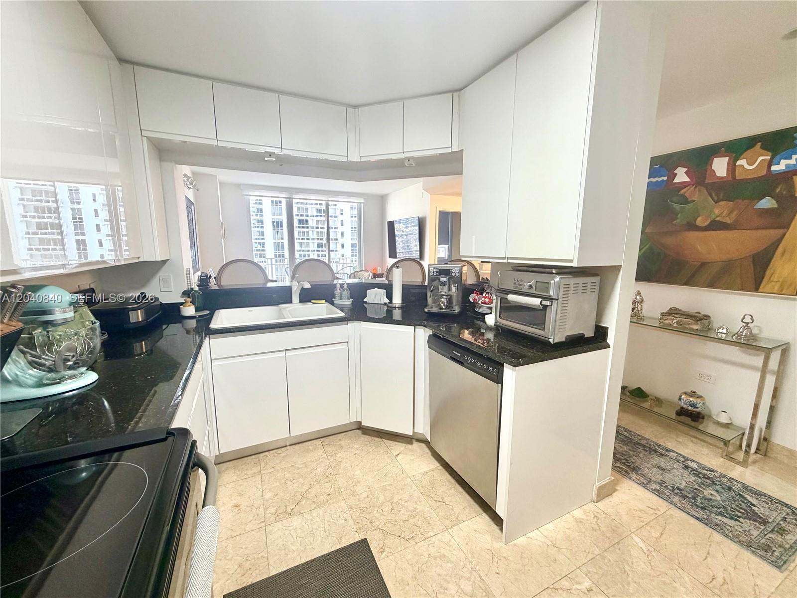 A kitchen features white cabinets, black countertops, stainless steel appliances, and a pass-through window — 801 Brickell Key Blvd # 1704, Miami FL 33131, MIAMI, FL