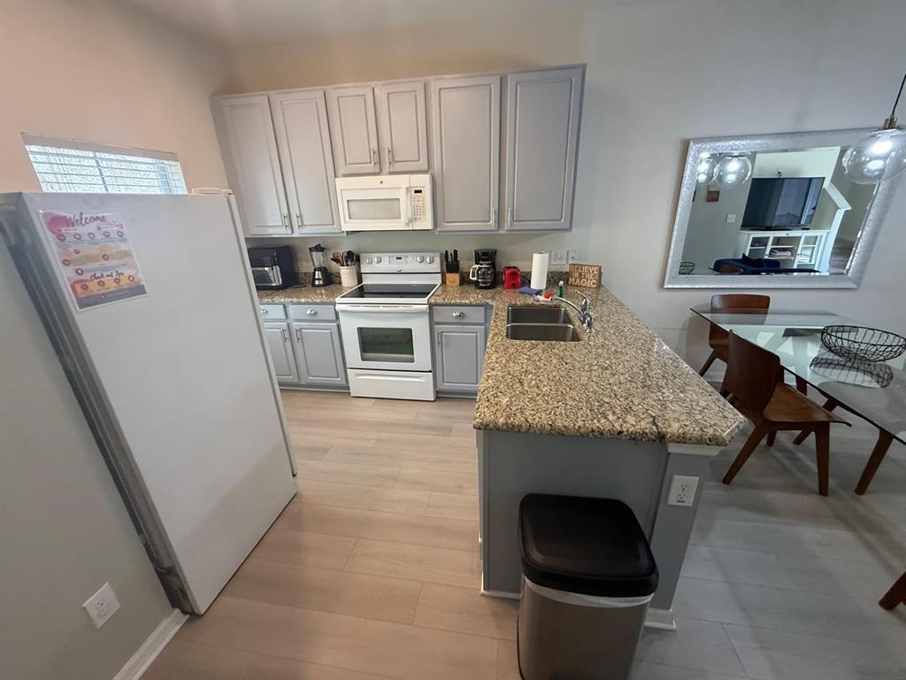 A kitchen features gray cabinets, granite countertops, white appliances, and a dining area — 4564 ADA LANE, KISSIMMEE, FL