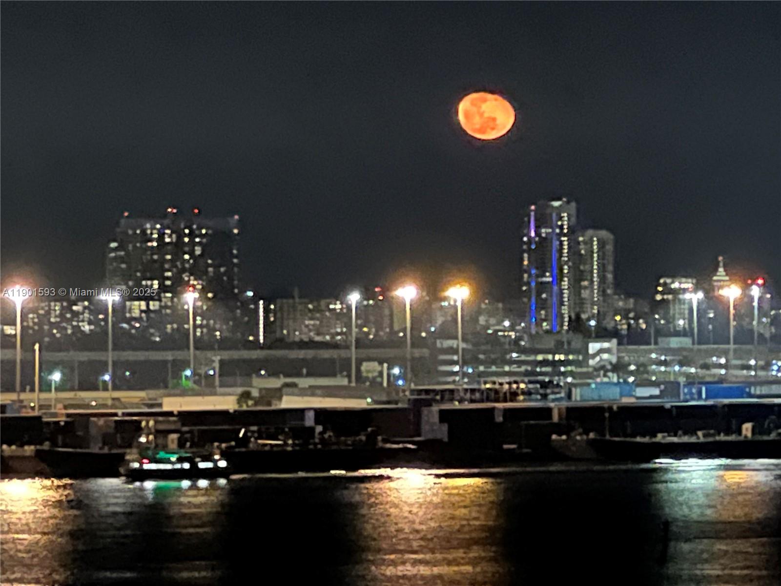 A night view of a city skyline with a large orange moon above the water — 520 Brickell Key Dr # A900, Miami FL 33131, MIAMI, FL