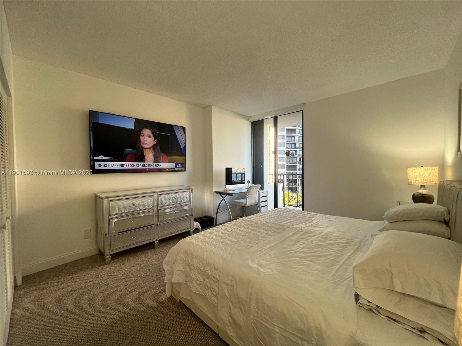 A bedroom features a bed, a mirrored dresser, a wall-mounted television, and a small desk — 520 Brickell Key Dr # A900, Miami FL 33131, MIAMI, FL