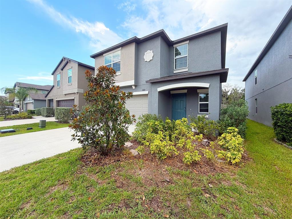 A two-story gray house with a blue front door and a landscaped front yard — 2122 STELLAR BRILLIANCE WAY, LUTZ, FL