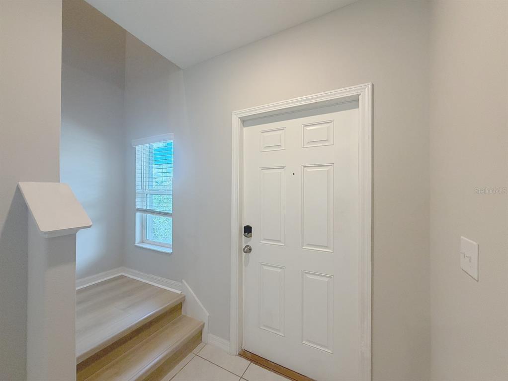 An entryway features a white front door, light wood stairs, and a window with blinds — 2122 STELLAR BRILLIANCE WAY, LUTZ, FL