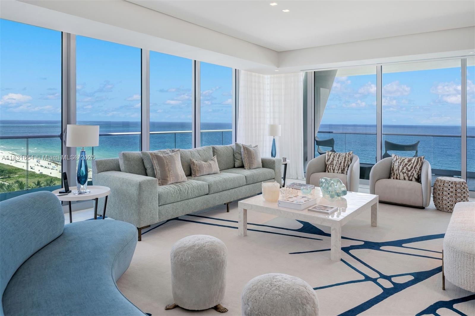 A modern living room features floor-to-ceiling windows with panoramic ocean views and neutral furnishings — 9349 Collins Ave # 1101, Surfside FL 33154, SURFSIDE, FL