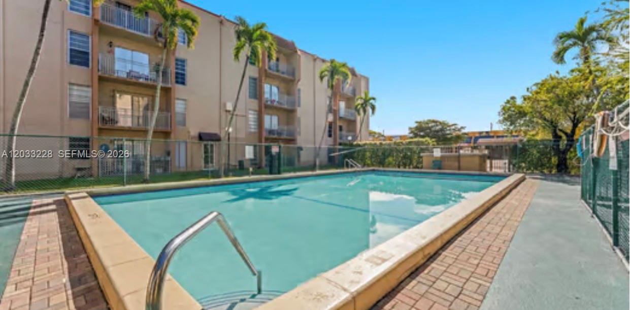 An outdoor swimming pool sits in front of a multi-story apartment building with palm trees — 4841 NW 7th St # 4, Miami FL 33126, MIAMI, FL