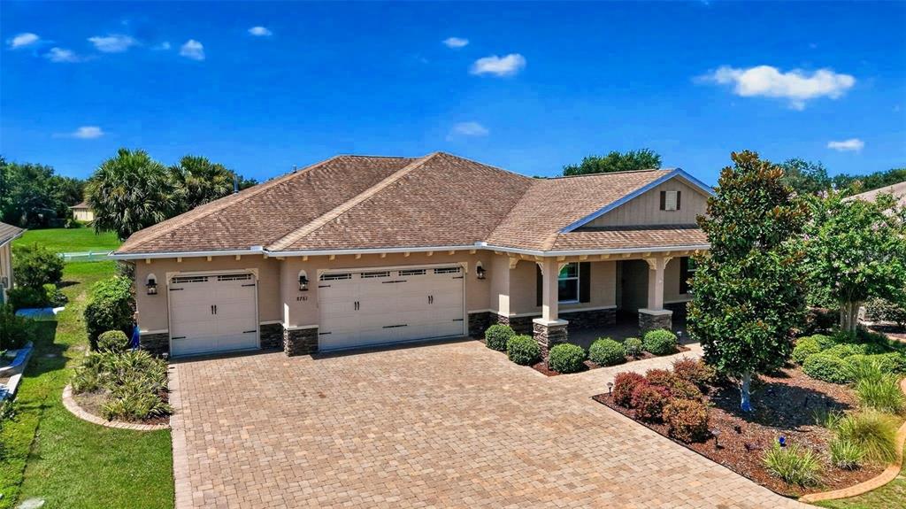 A single-story house with a tan exterior, a brown shingled roof, and a paved driveway — 8761 SW 93RD CIRCLE, OCALA, FL