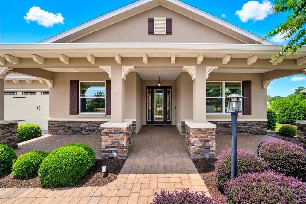 The exterior of a single-story house featuring a stone-accented porch, columns, and a paved walkway — 8761 SW 93RD CIRCLE, OCALA, FL