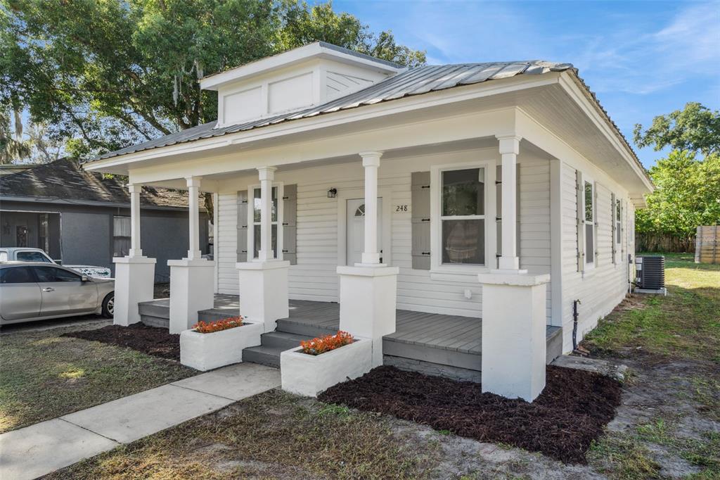 A white, single-story bungalow with a covered front porch, metal roof, and gray shutters — 248 E MAGNOLIA STREET, GROVELAND, FL