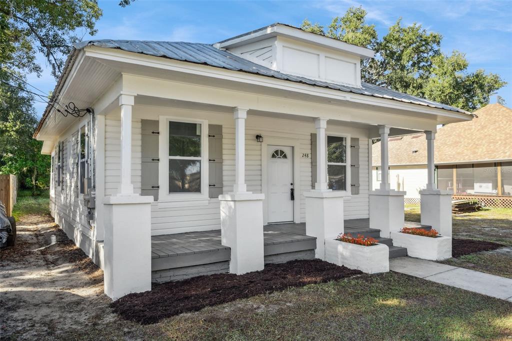 A white, single-story house features a front porch with columns and a metal roof — 248 E MAGNOLIA STREET, GROVELAND, FL