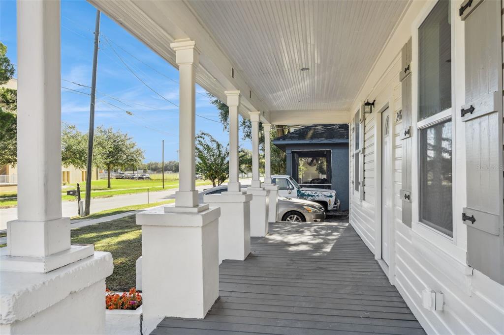 A covered front porch with white columns and wooden decking overlooks a street — 248 E MAGNOLIA STREET, GROVELAND, FL