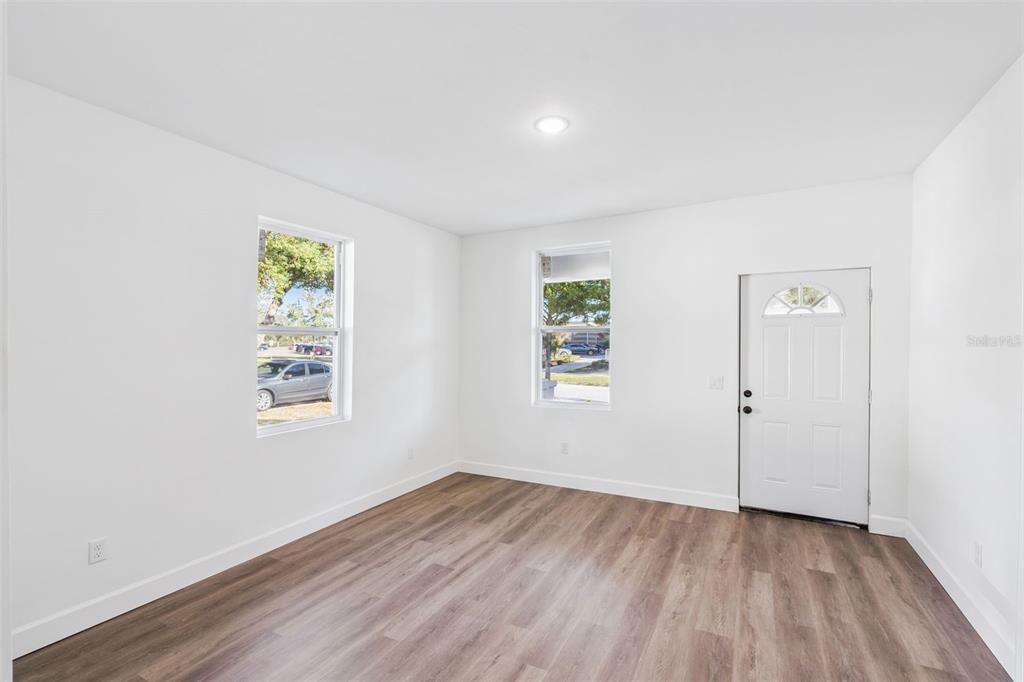 An empty room with white walls, wood-look flooring, two windows, and a white entry door — 248 E MAGNOLIA STREET, GROVELAND, FL