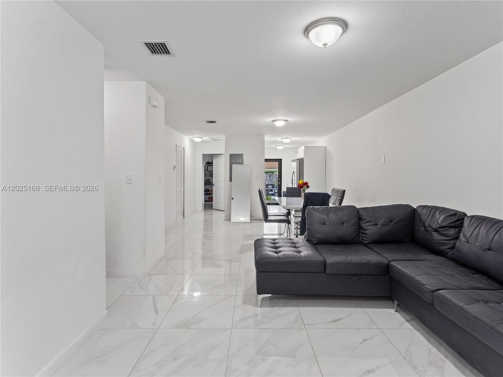 A living room with a black sectional sofa and white marble-style tile flooring — 10769 SW 146th St, Miami FL 33176, MIAMI, FL